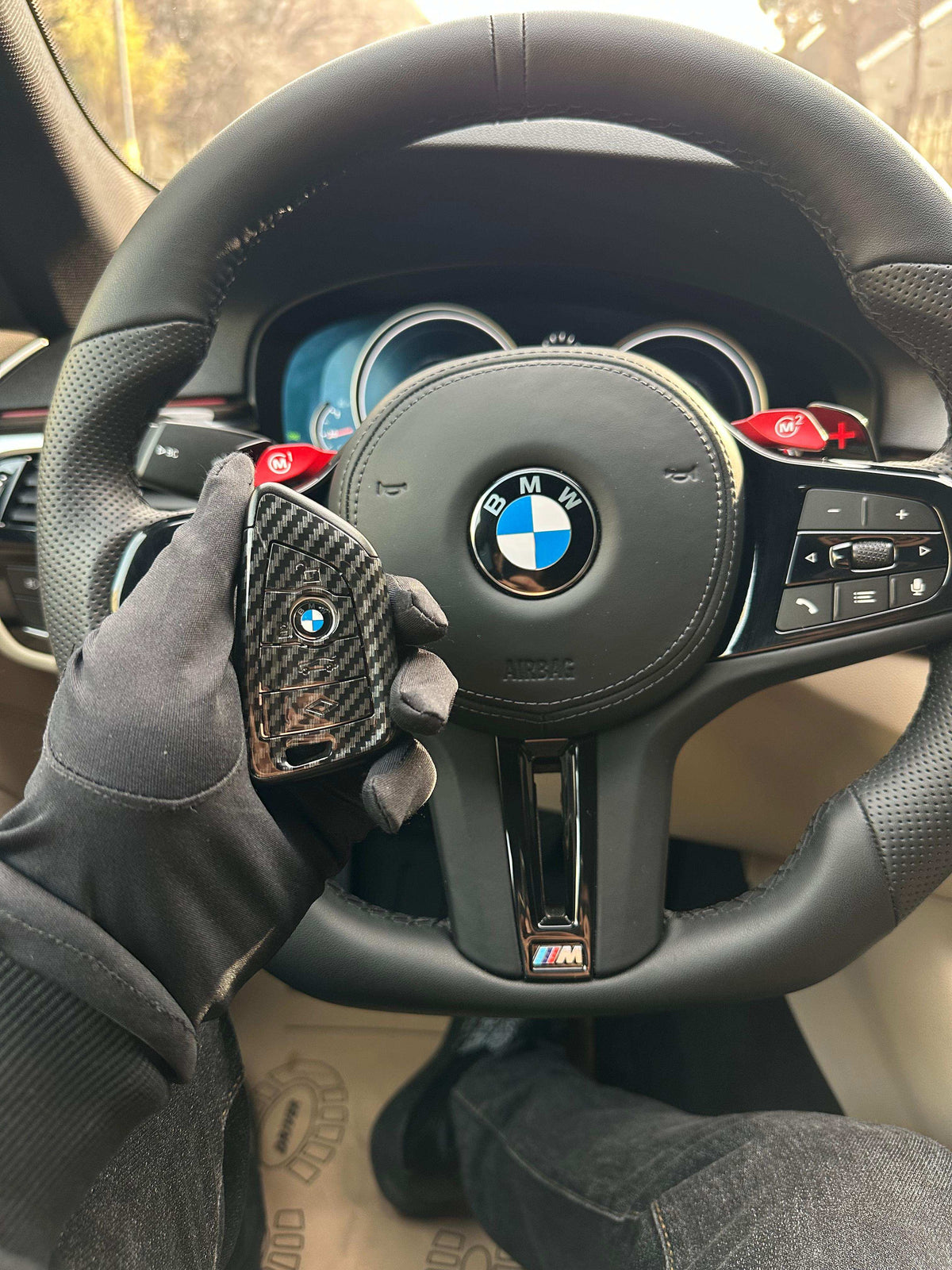 BMW carbon fiber key cover held in hand on steering wheel
