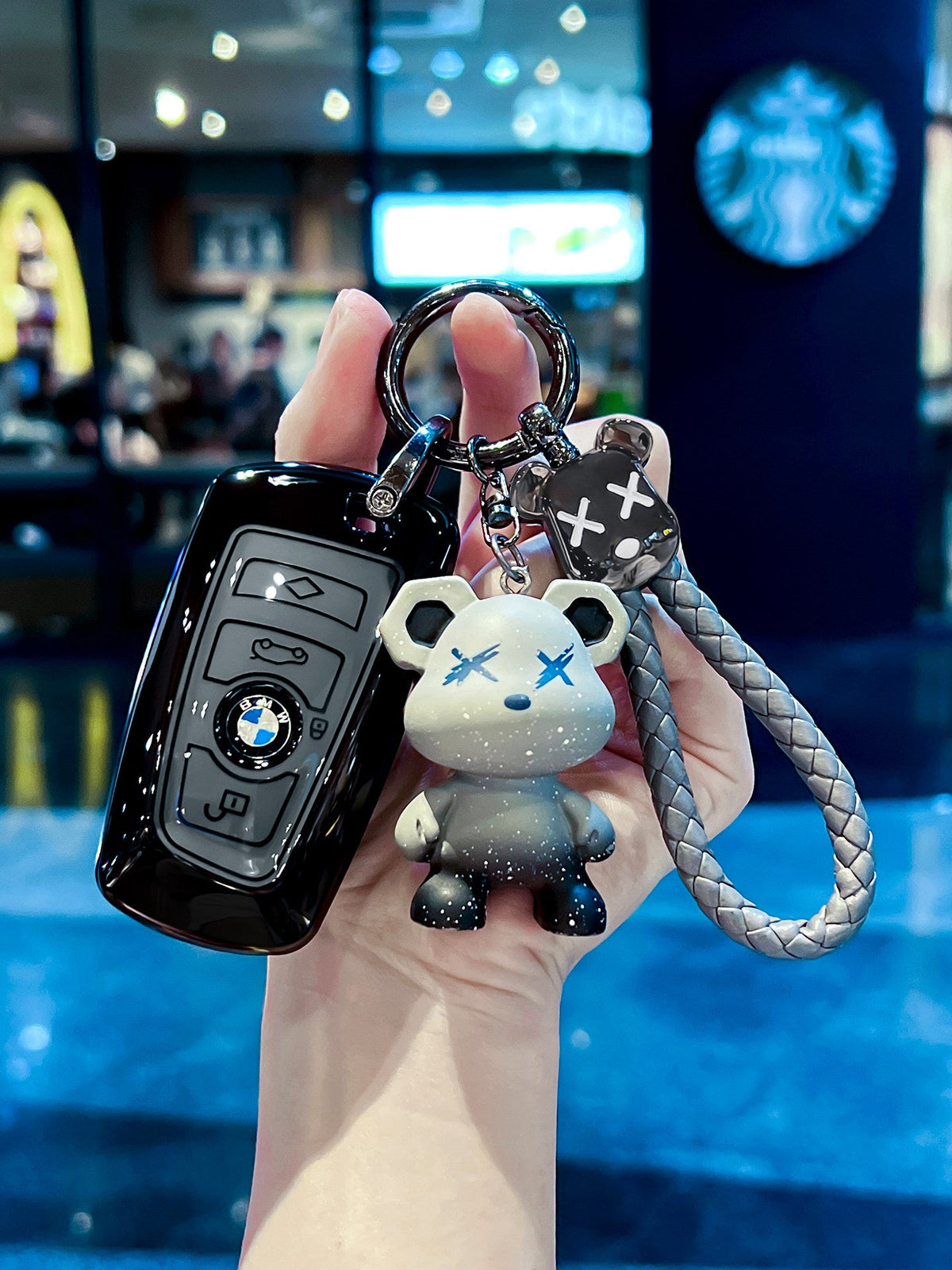 BMW smart key in glossy black TPU sleeve with bear keychain charm, front view