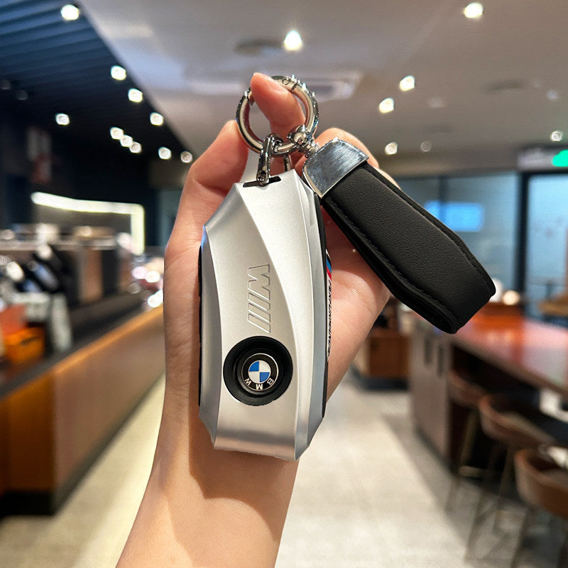 BMW key case silver with black cord strap keychain held in hand