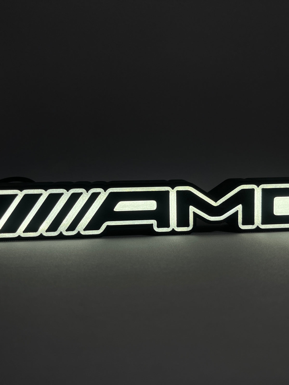 Mercedes-AMG illuminated emblem lamp glowing white in a dark room