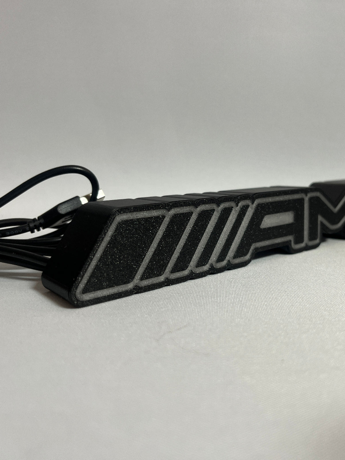 Mercedes-AMG emblem desk lamp with USB cable – angled view of the 3D-printed AMG logo