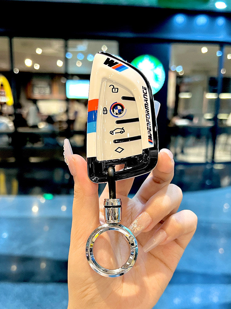 BMW smart key fob in white TPU protective case with tricolor M Sport stripe, front view close-up