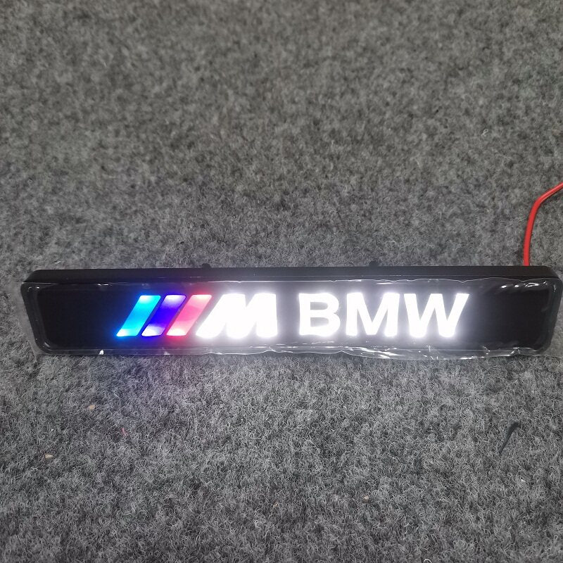 M BMW LED grille badge with tri-color stripes illuminated