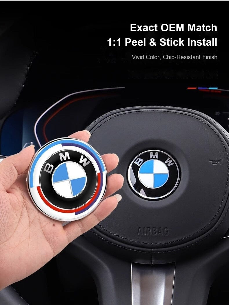 BMW steering wheel badge held in hand next to installed factory badge