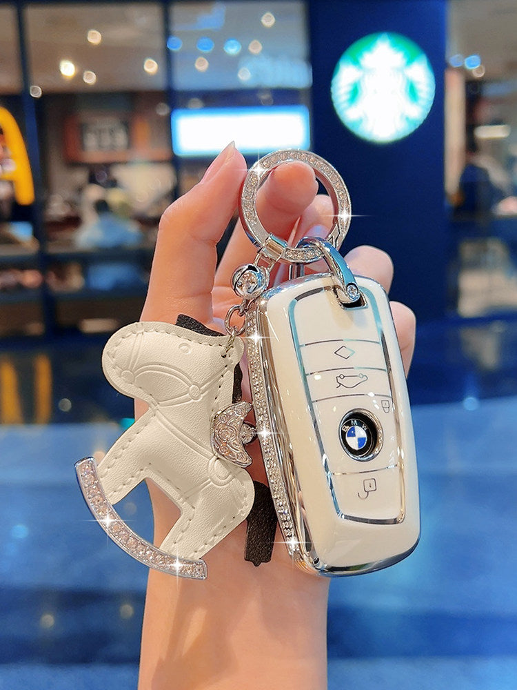 BMW diamond-studded cream white TPU key case held in hand, side angle