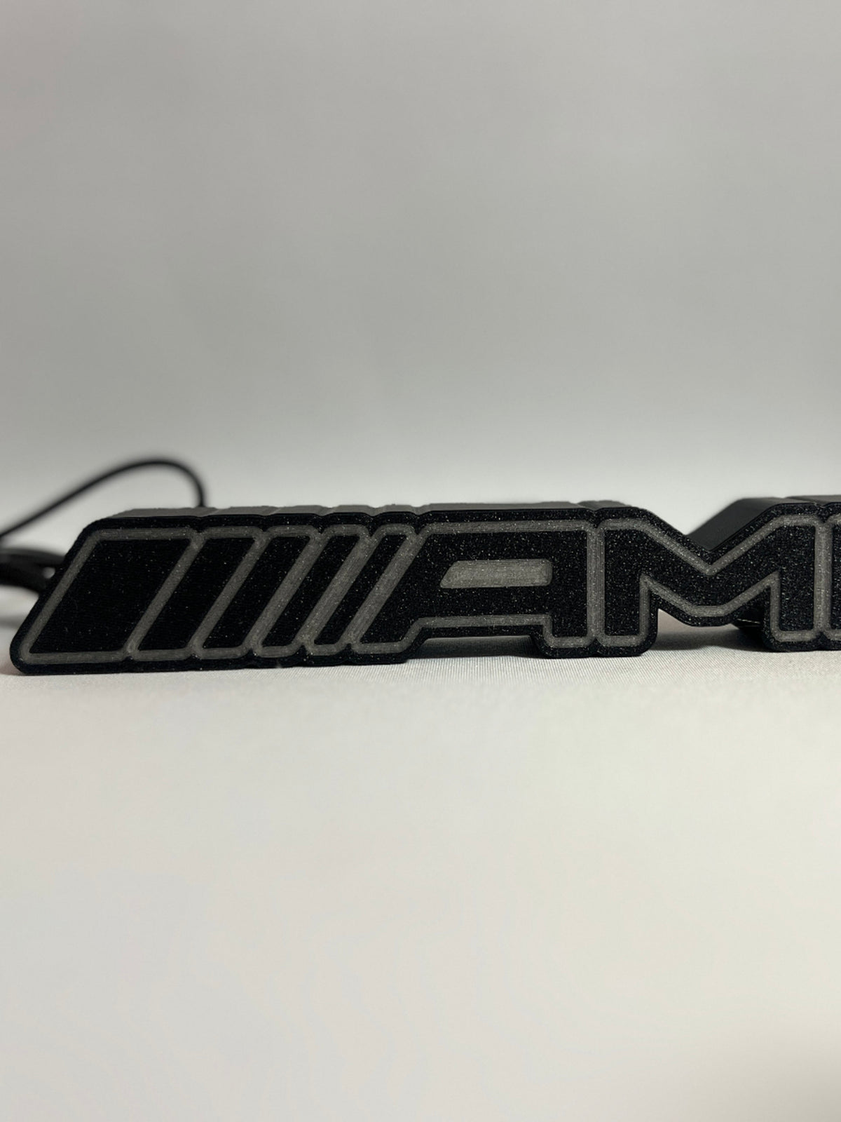Mercedes-AMG 3D-printed emblem lamp switched off – textured black body with light outline