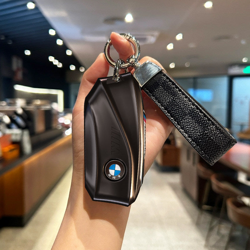 BMW key case gunmetal black with black plaid strap keychain held in hand