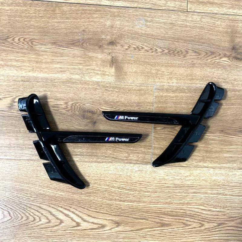 Gloss black BMW fender side vent pair on wood floor