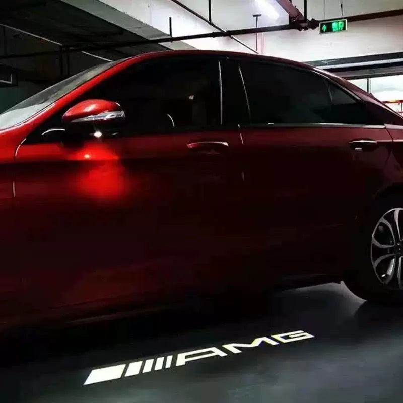 AMG logo light carpet projected under the side mirror of a red Mercedes-Benz