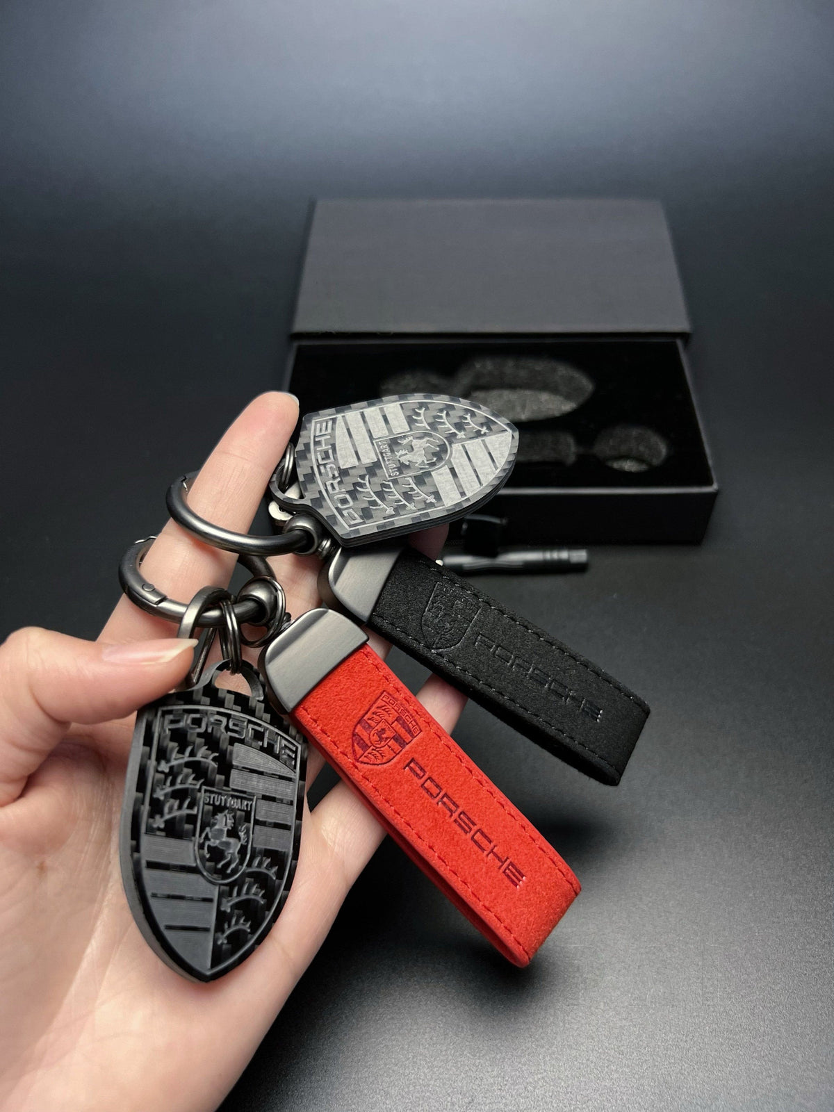 Porsche carbon fiber crest keychain with red and black suede straps
